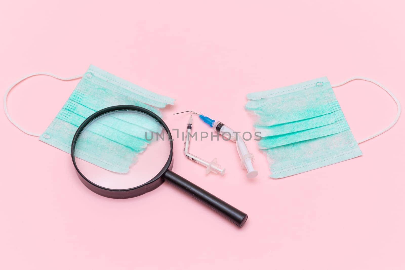 Anti Vaccine Movement and Anti Mask Concept - Broken Medical Syringe and Green Torn Medical Face Mask with Magnifying Glass on the Pink Background. Pandemic and Lockdown End - Top View, Flat Lay