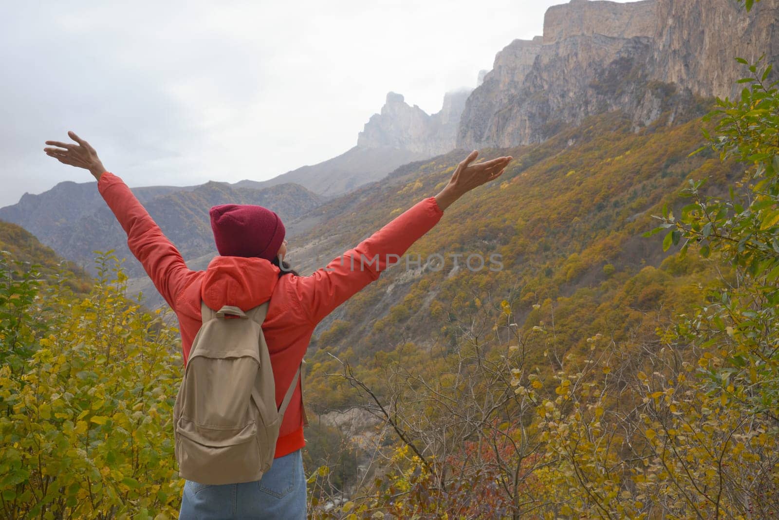 Woman outdoors exploring the Caucasus Mountains in Russia, travel, lifestyle, hiking, girl traveler raised her hands, active autumn holidays, hiking.