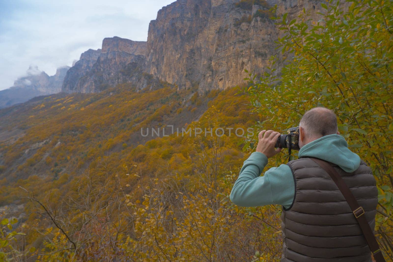 a tourist takes pictures of a beautiful autumn mountain landscape using a camera.