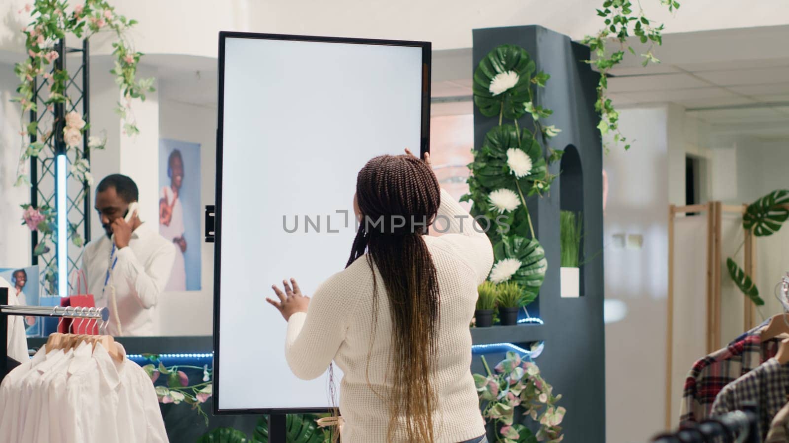 Woman looks at clothes on store kiosk by DCStudio