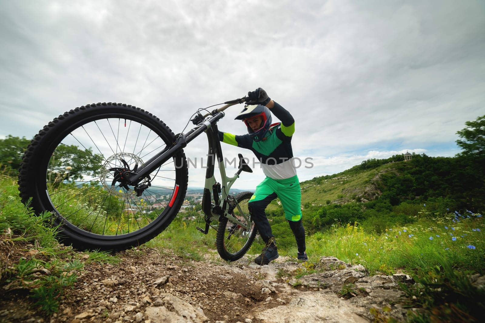 A man pushes a mountain bike up a hill. Adventure travel by bike. Guy athlete in defense lifts his equipment by yanik88