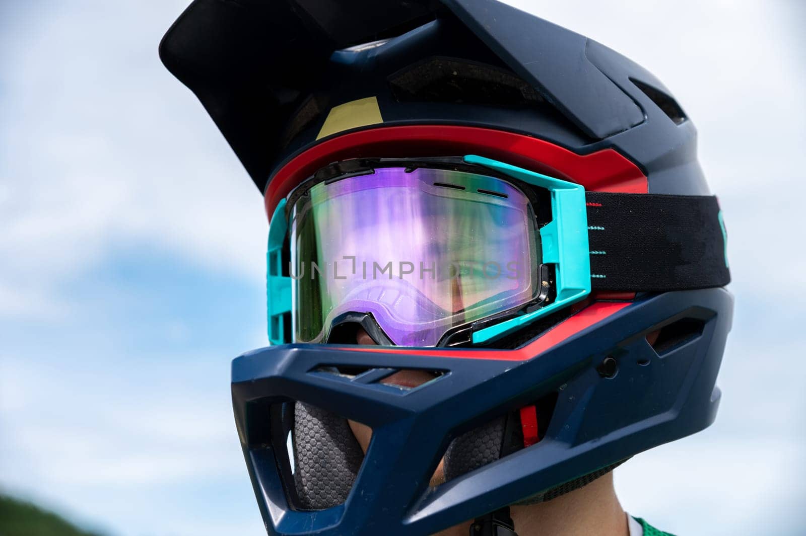 Portrait of a cyclist in a full-face helmet and goggles against the sky. The athlete's happy and joyful eyes are visible through the mask by yanik88