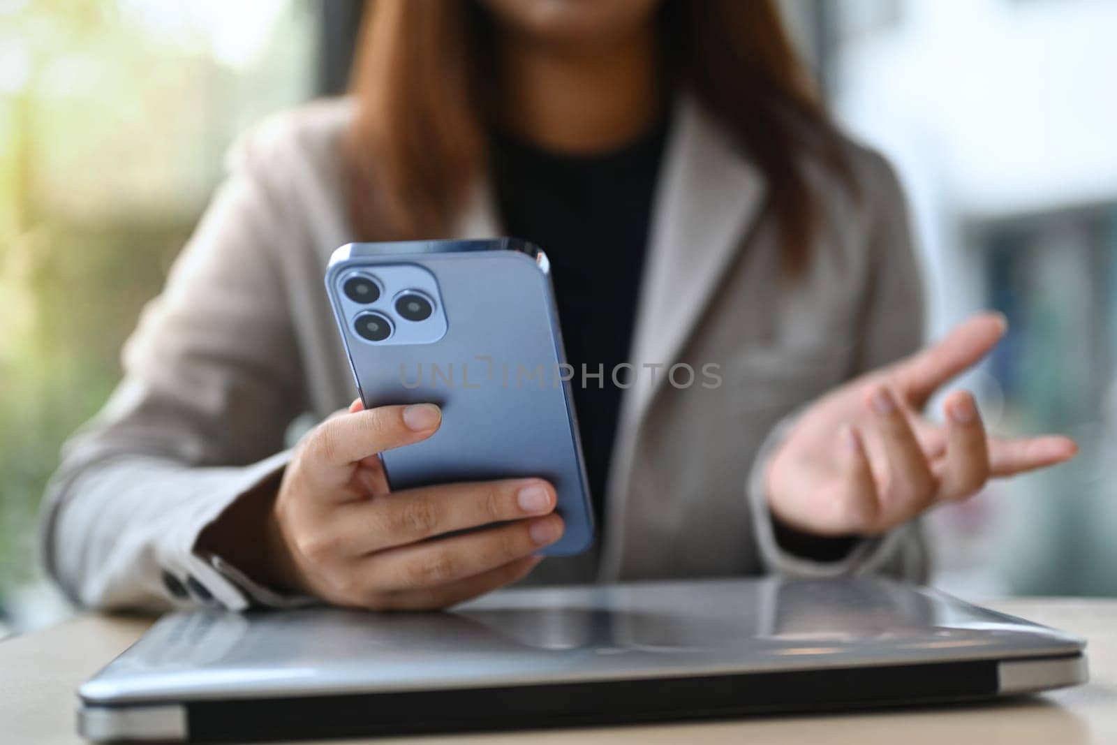 Young female employee sitting at desk and using mobile phone. Technology and lifestyle concept.
