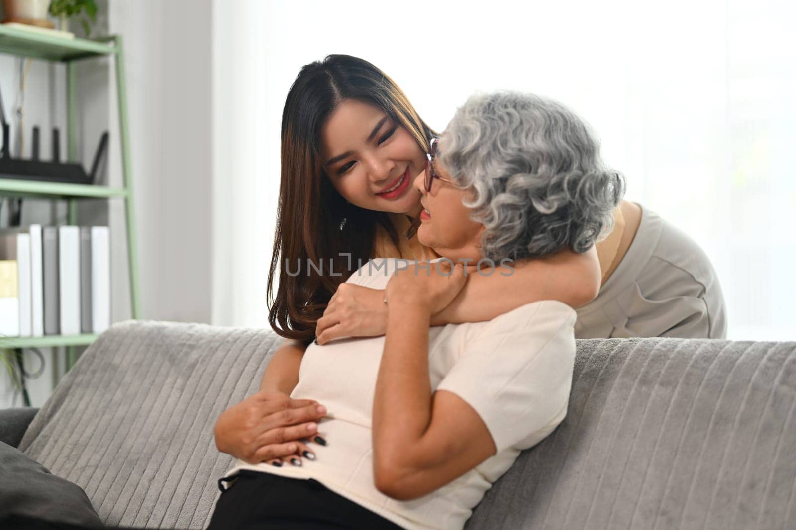 Loving daughter hugging middle aged mother from back. Family bonding concept.