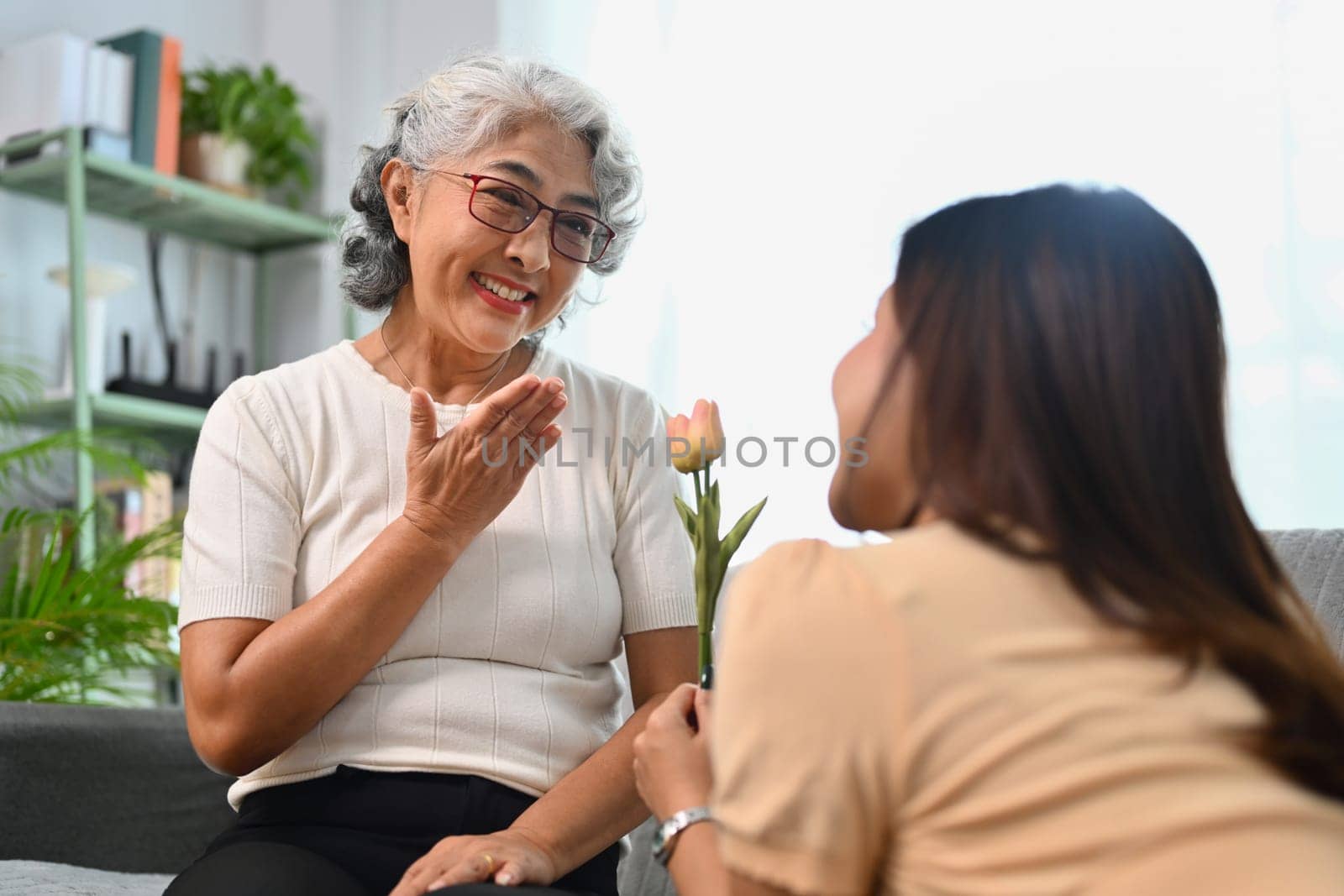 Grateful happy mature mother receiving flowers from grownup daughter. Happy Mothers Day concept.