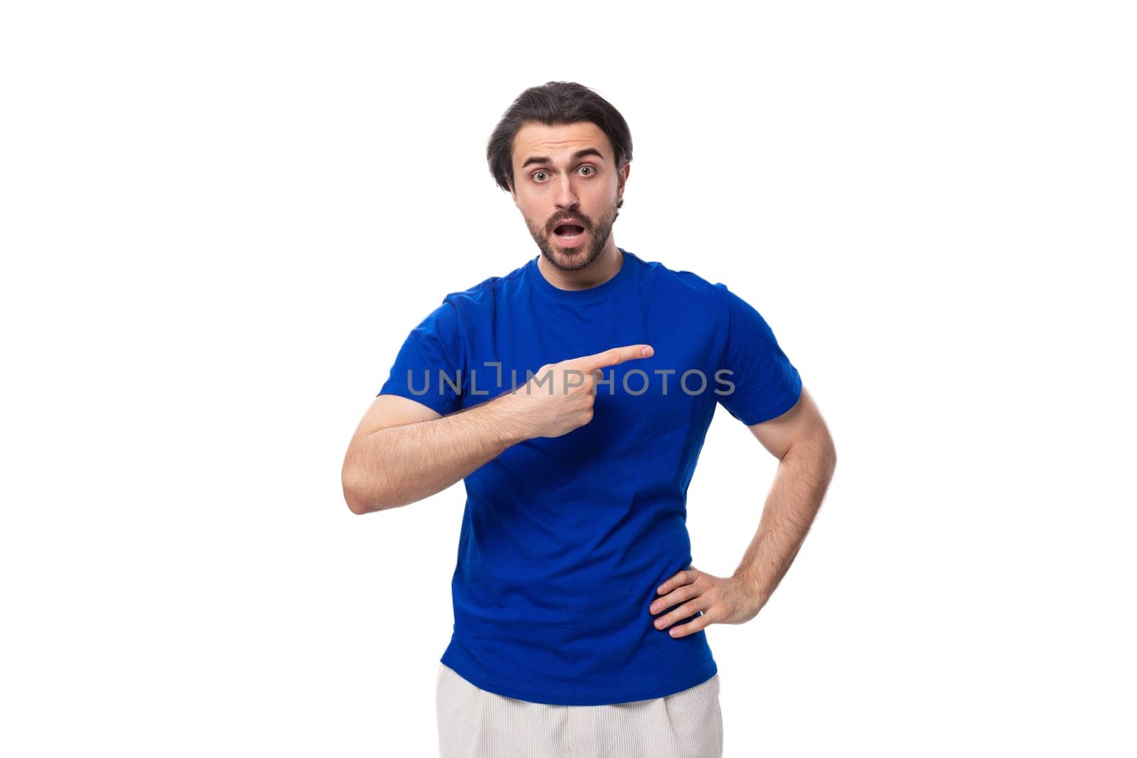 young authentic brunette man with a beard in a blue t-shirt on a white background with copy space by TRMK