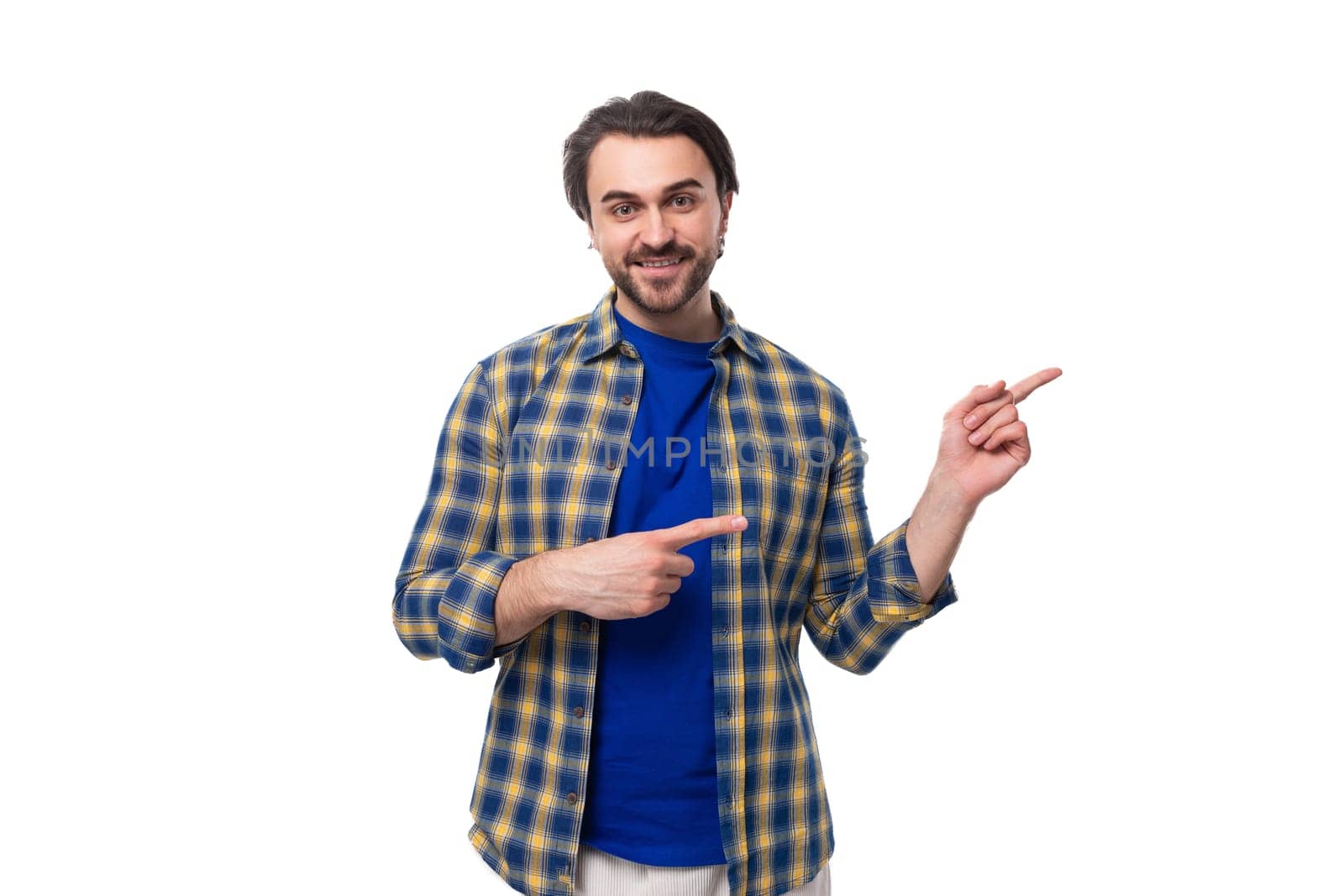 handsome brunet macho man with a beard in a blue shirt on a white background with copy space.