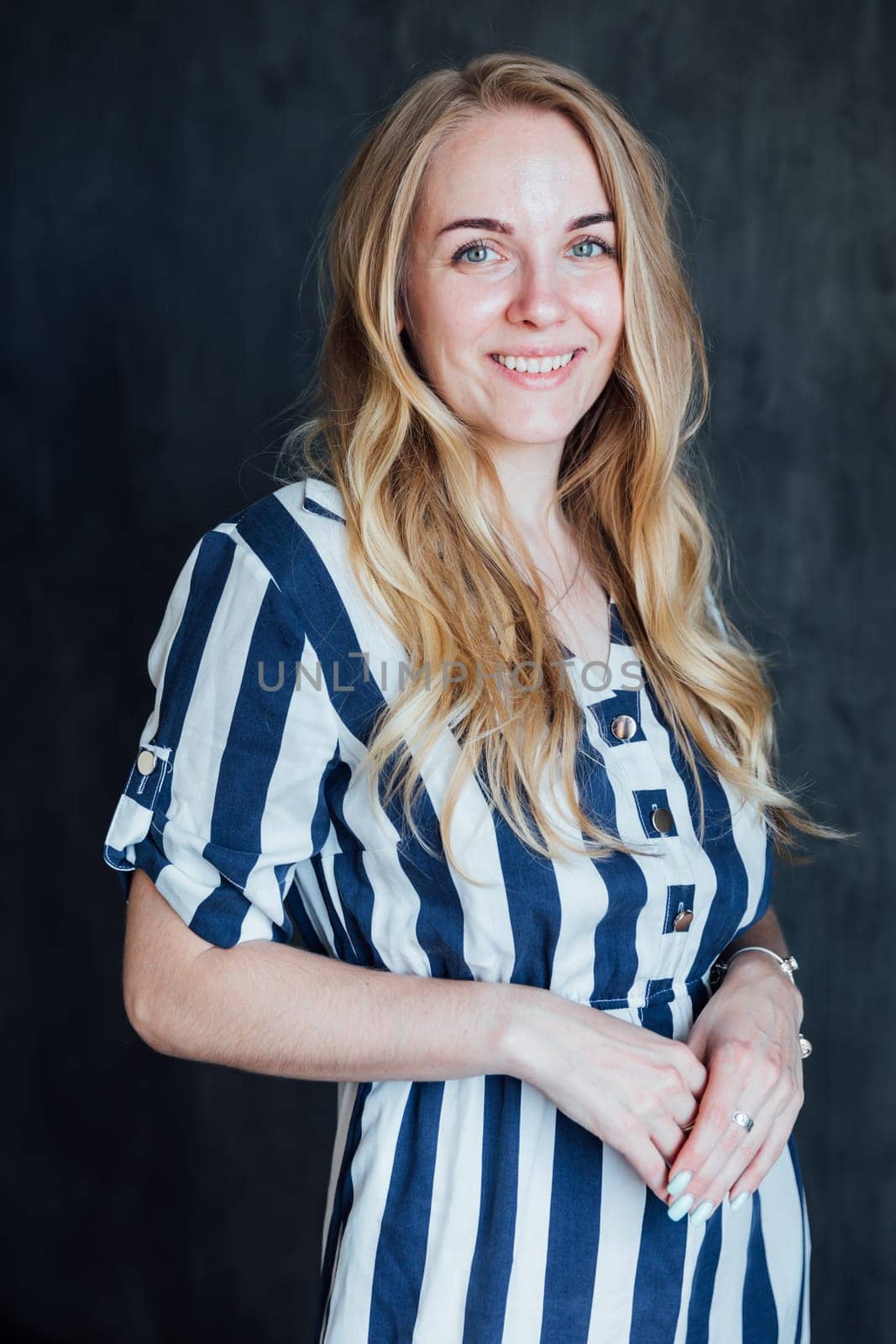 Portrait of a beautiful young blonde woman in a striped summer dress by Simakov