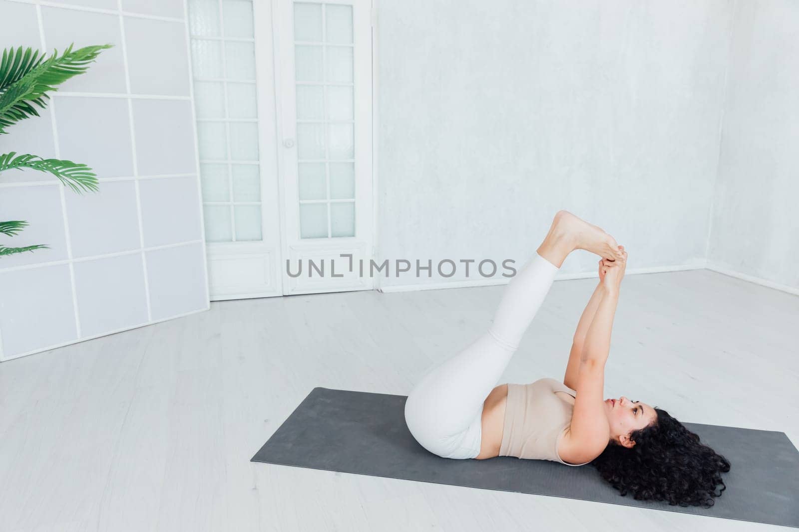 Attractive young woman doing yoga stretching yoga online at home. Self-isolation is beneficial, by Simakov