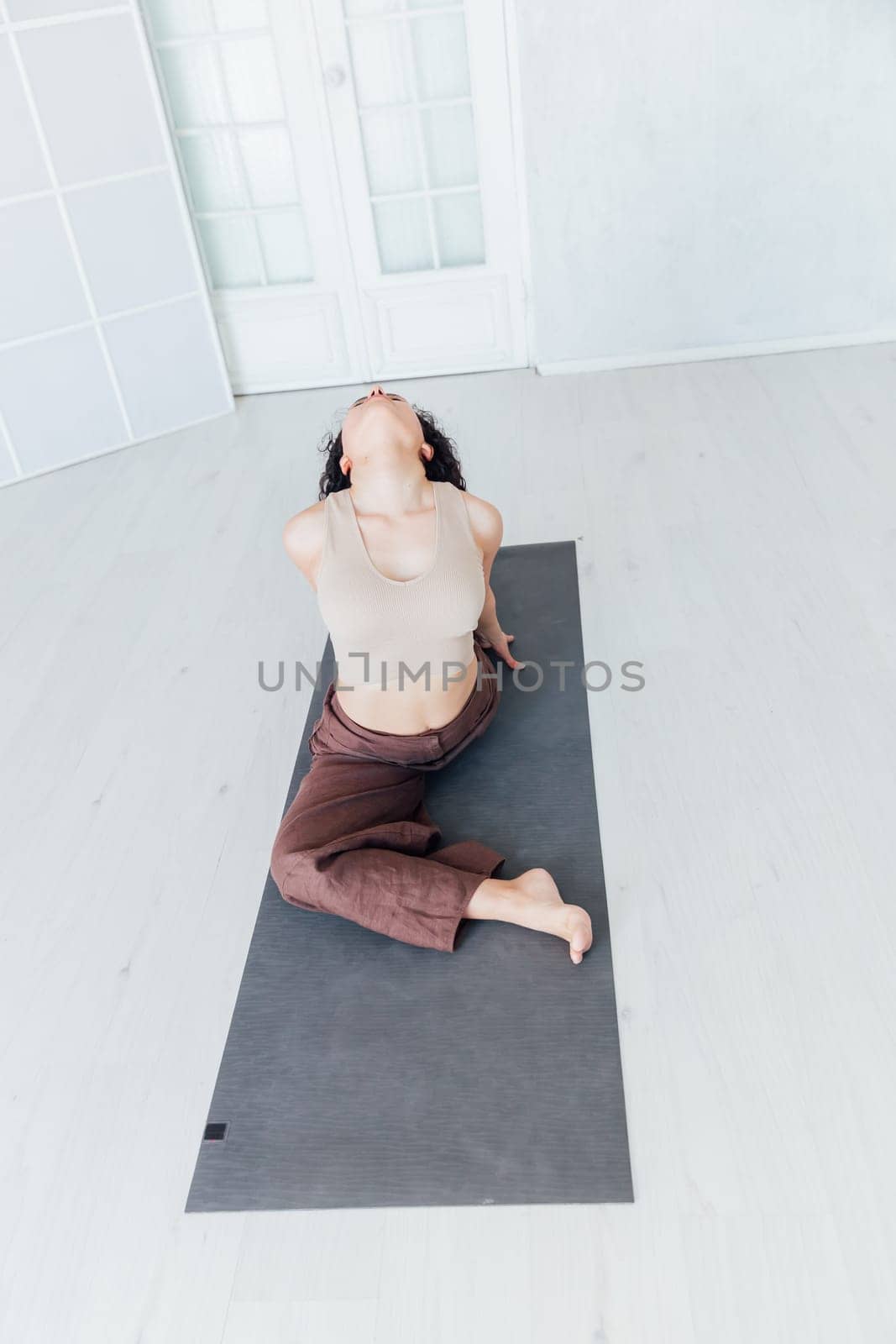 Stay at home fitness. Strong mature woman doing half bridge yoga pose, strengthening her abs muscles indoors, by Simakov