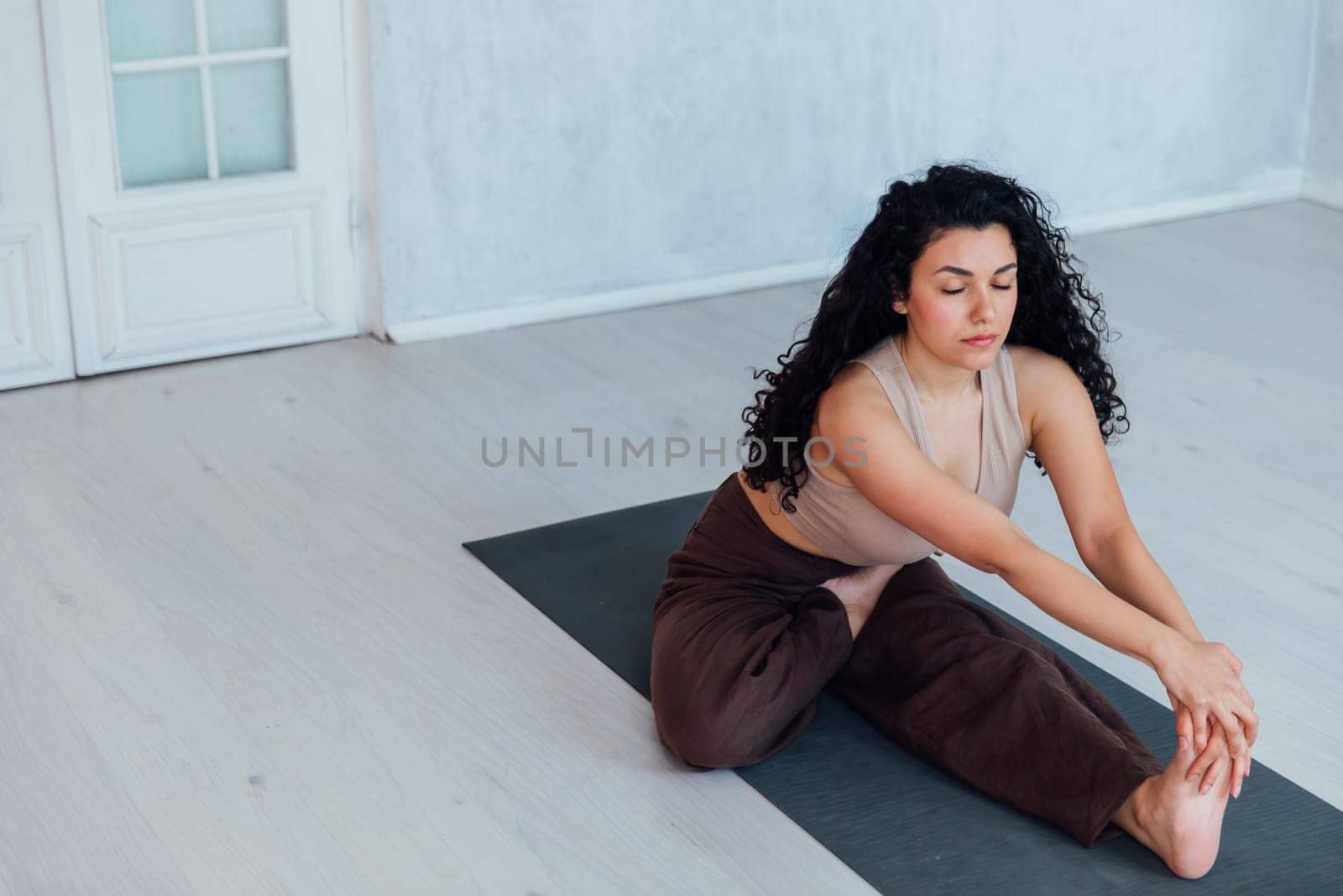 Fit woman making cobra pose on yoga mat, exercising in studio by Simakov