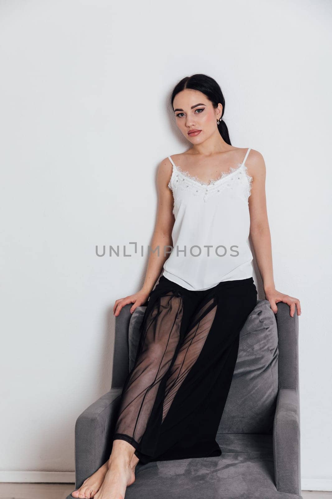 fashionable woman in black pants sits on a chair