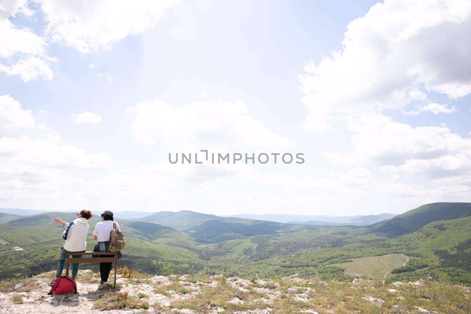 two people sitting on bench on a mountain hiking journey nature