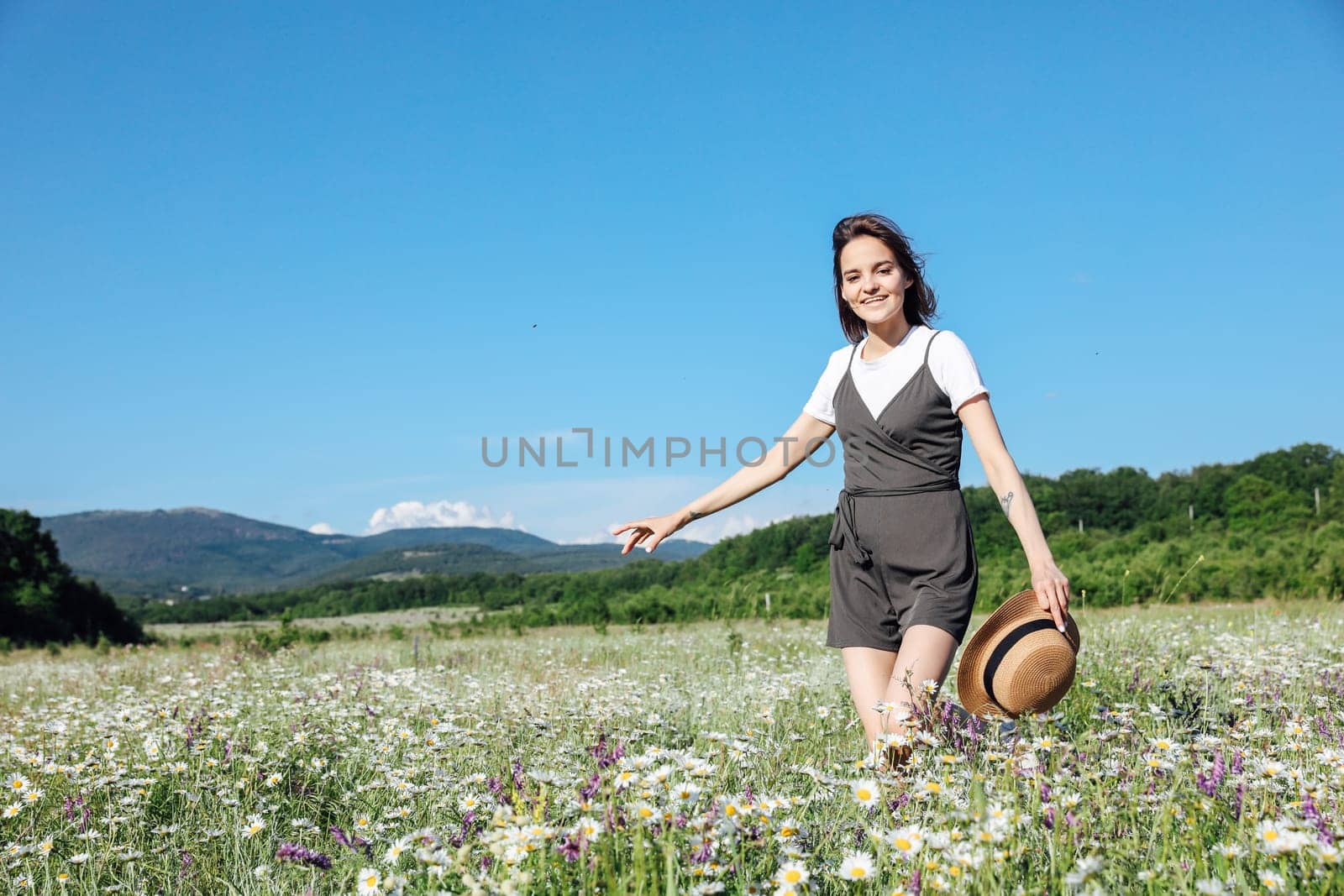 in nature, a woman with a hat runs into a field with daisies flowers by Simakov