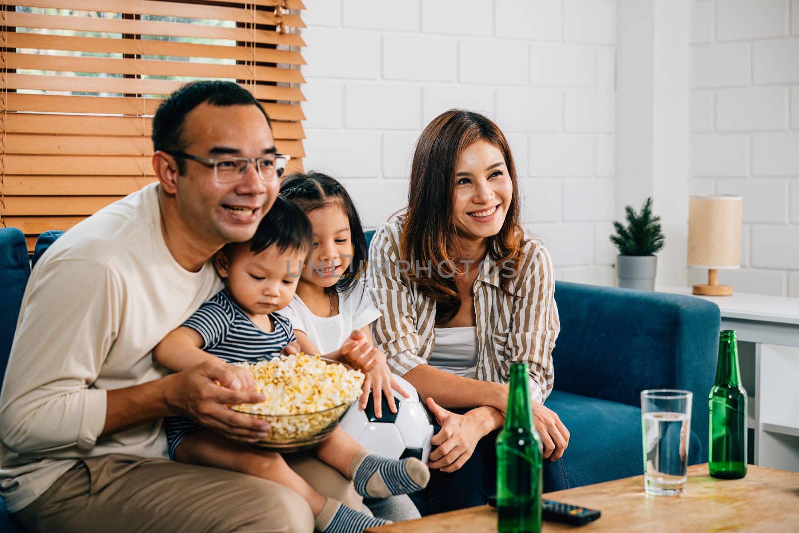 In their cozy living room, a joyful family and their daughter bond over a football match on TV. Their cheers, laughter, and togetherness reflect the joy of winning and celebrating a triumph.