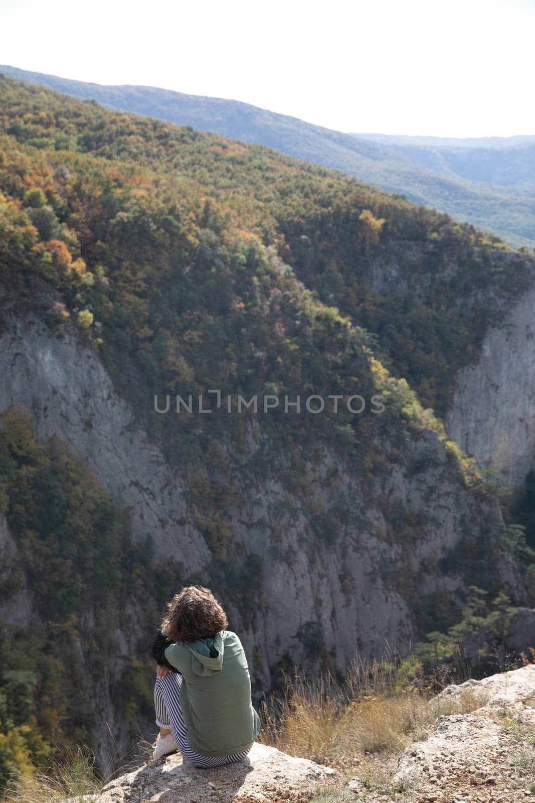 woman sitting on a mountain and looking up at the mountains nature hiking journey by Simakov