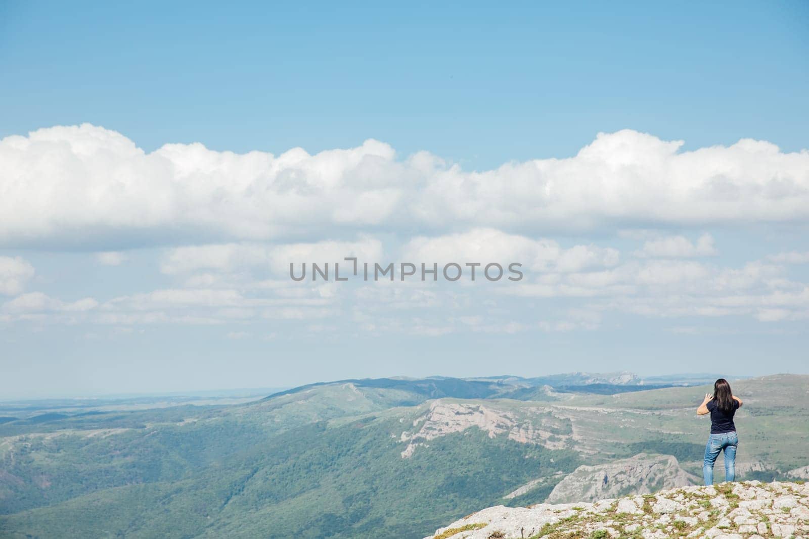 a woman standing on top of a mountain above a blue sky on a hike trip by Simakov