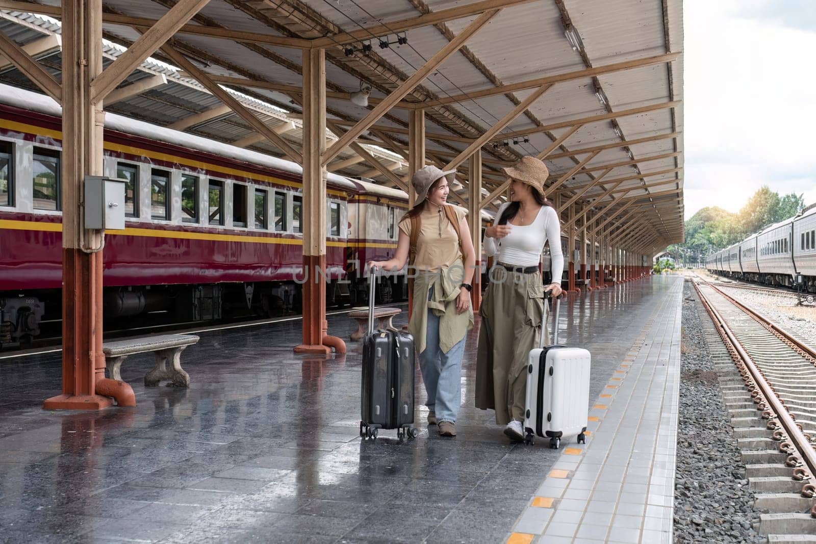 Young woman holding a suitcase waiting for a train at the train station while traveling on a weekend trip..