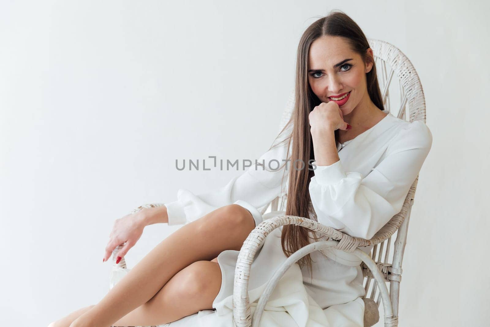brunette in white dress sits comfortably in a chair in a bright room by Simakov