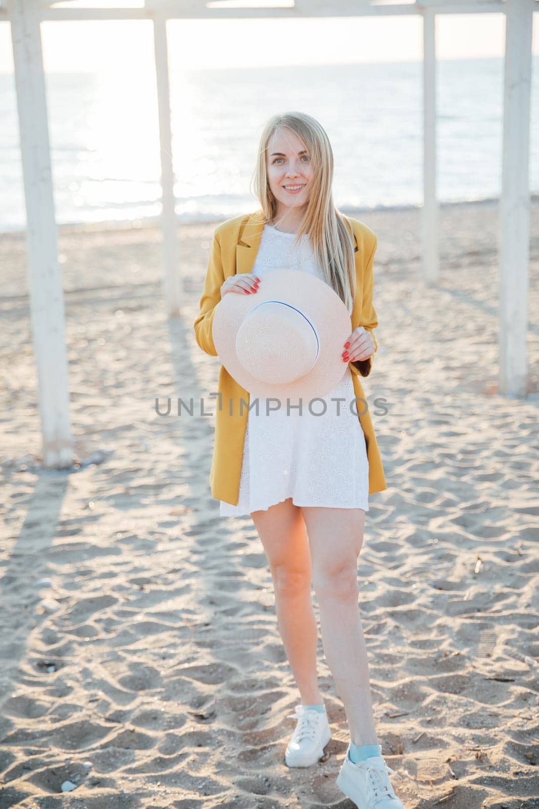 a blonde woman with hat in hand on the beach