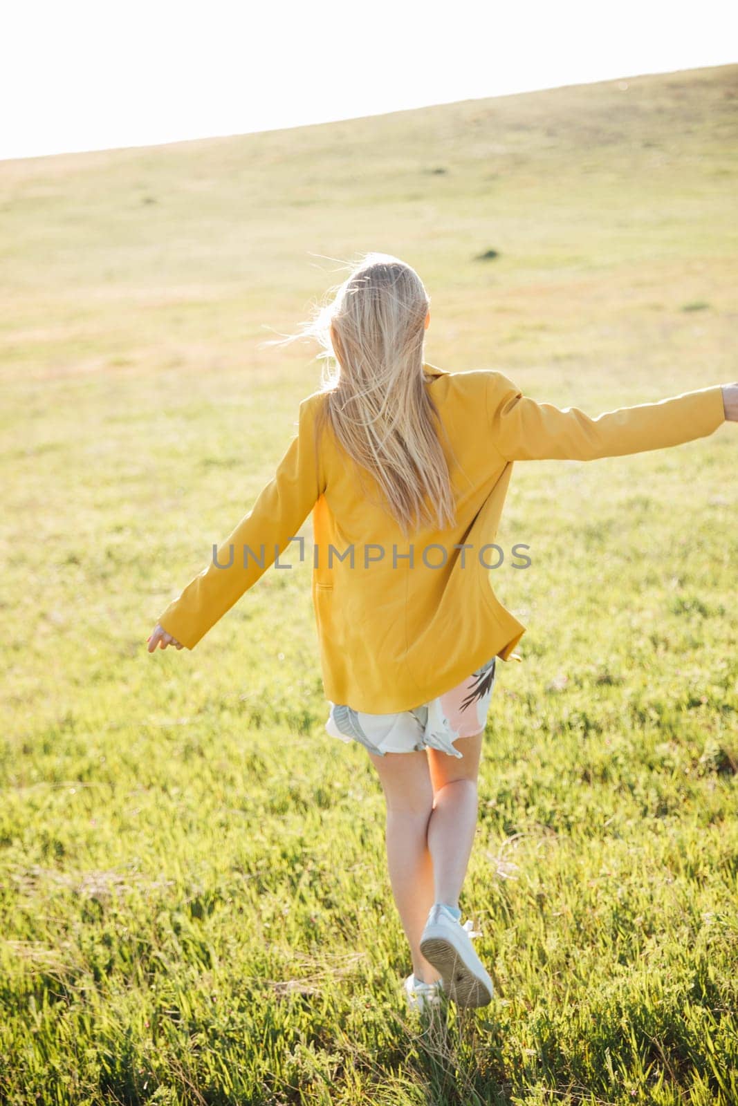 blonde woman walking in nature on green grass in field walking journey