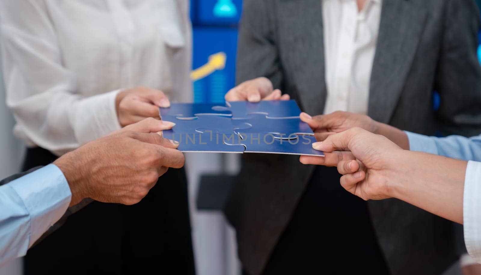 Corporate officer worker collaborate in office, connecting puzzle pieces with report paper on table as partnership and teamwork. Unity and synergy in business concept by merging jigsaw puzzle. Concord