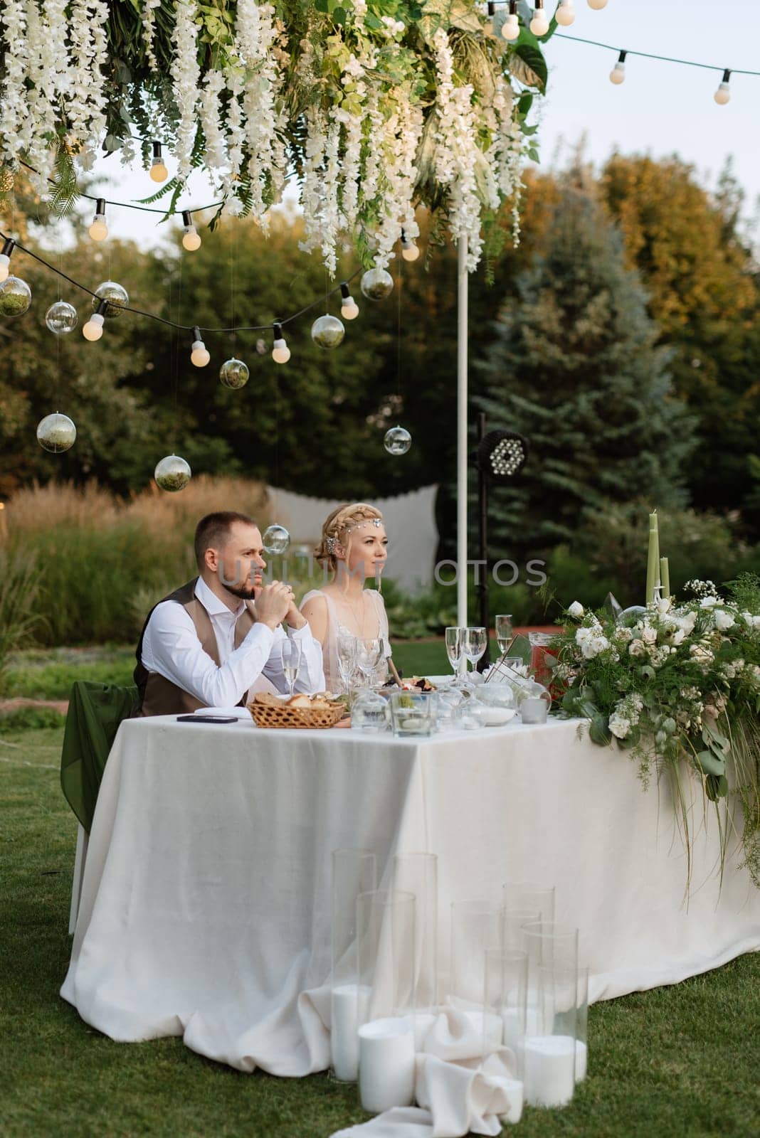 evening wedding family dinner in the forest with light bulbs and candles