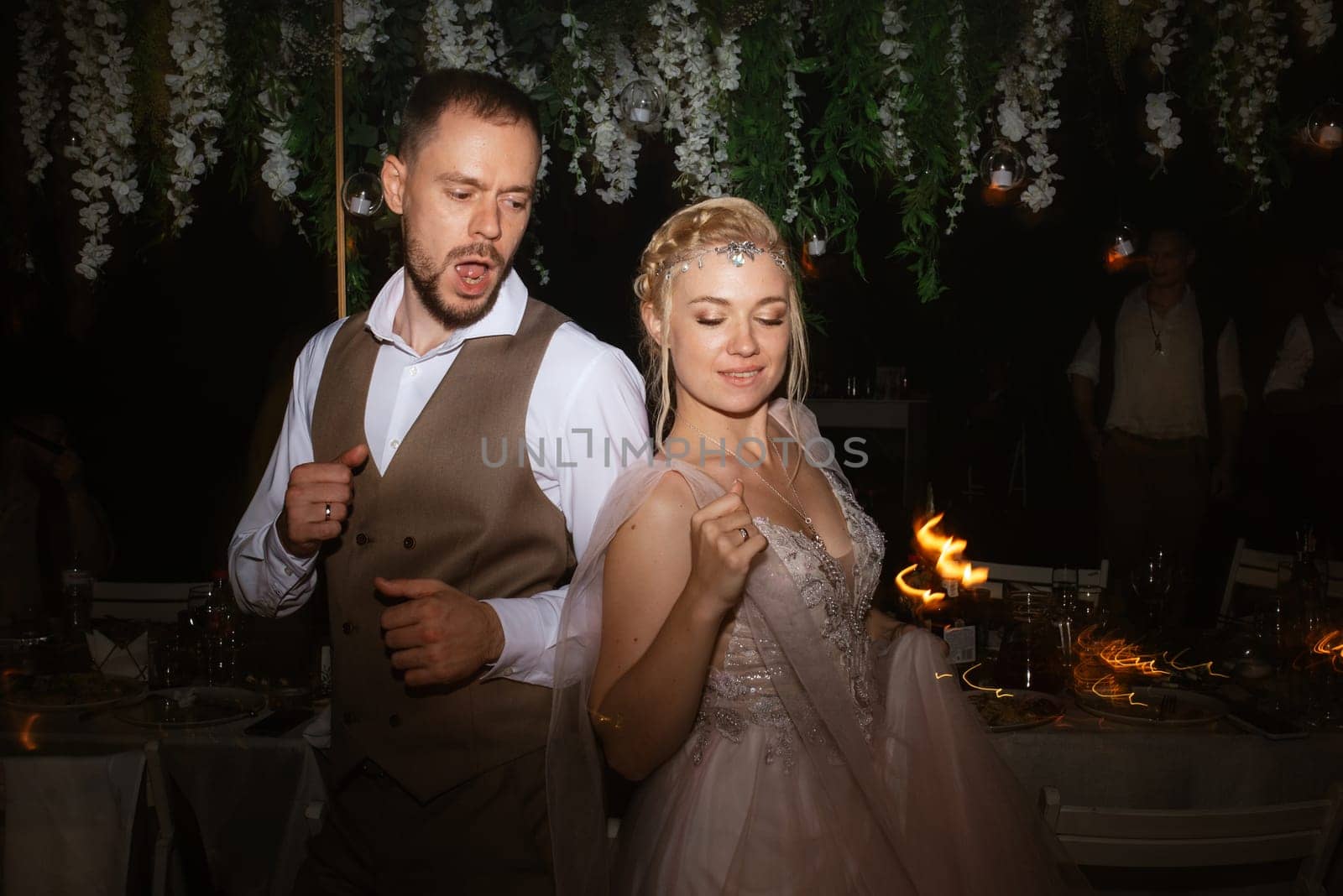 the first wedding dance of the bride and groom in the glade of the country club in the light of sunset and warm garlands