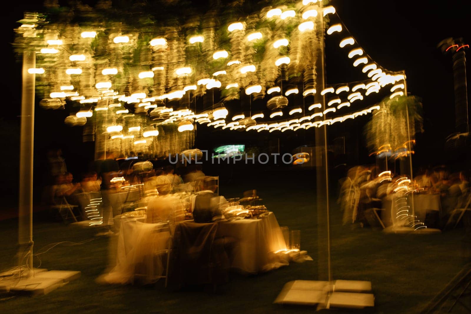 evening wedding family dinner in the forest with light bulbs and candles