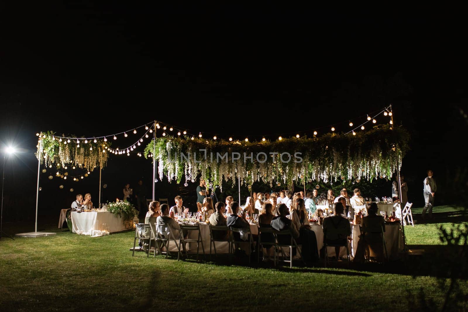 evening wedding family dinner in the forest with light bulbs and candles