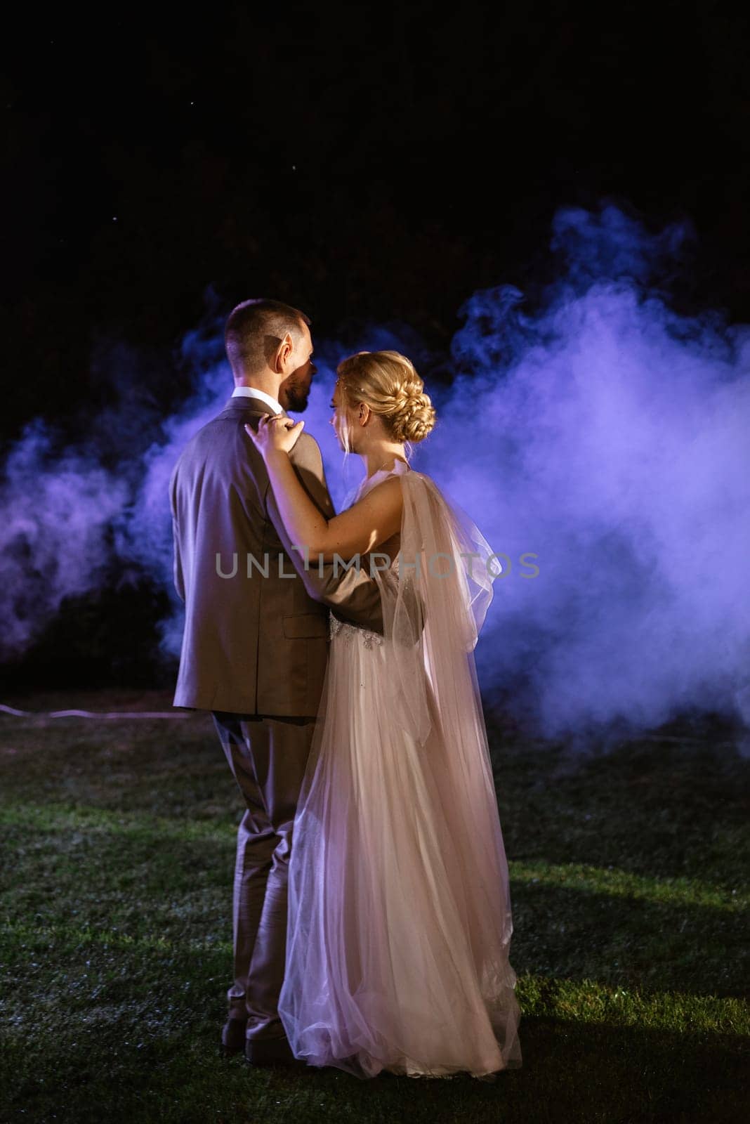 the first wedding dance of the bride and groom in the glade of the country club in the light of sunset and warm garlands