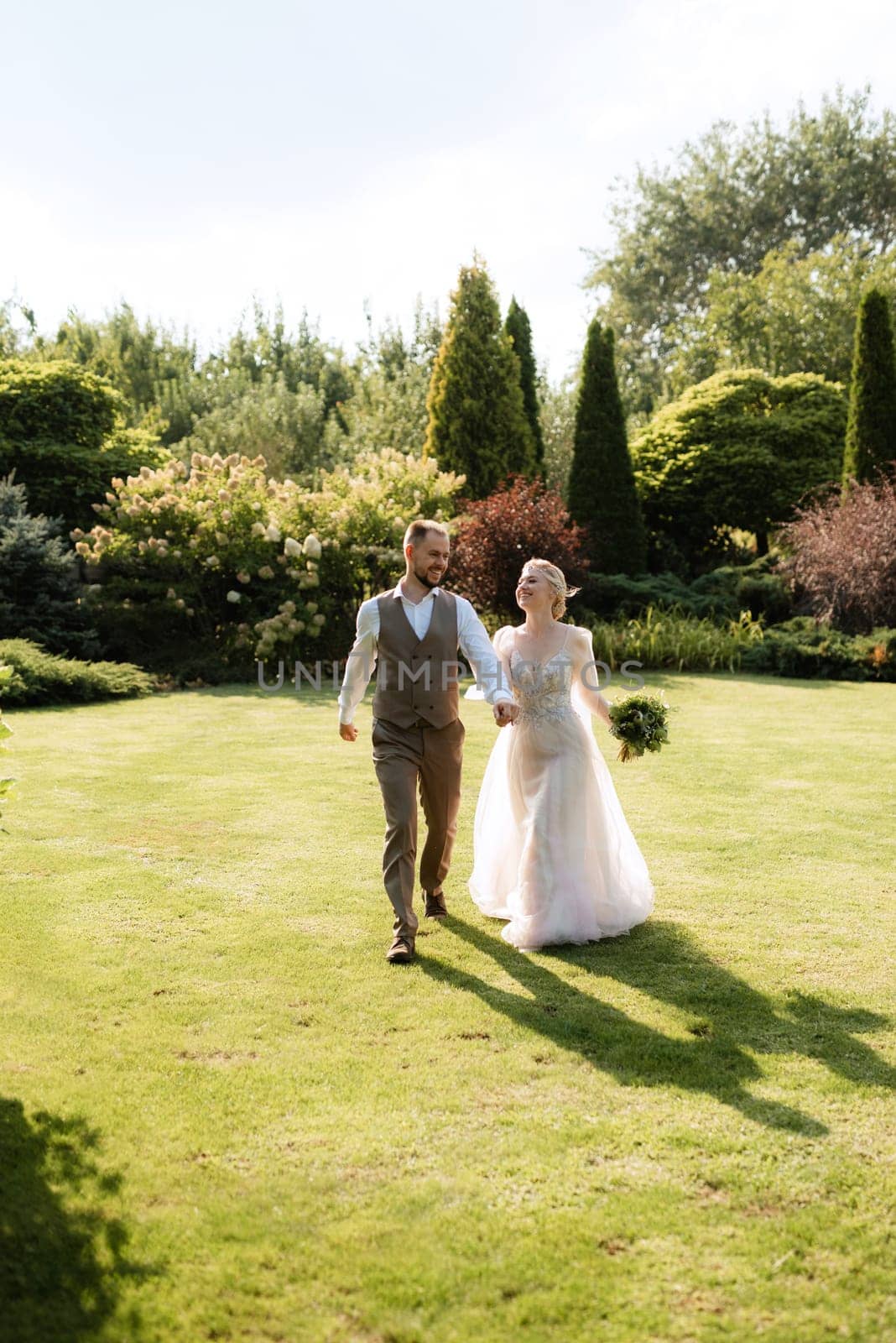 wedding walk of the bride and groom in a coniferous park in summer in elven accessories