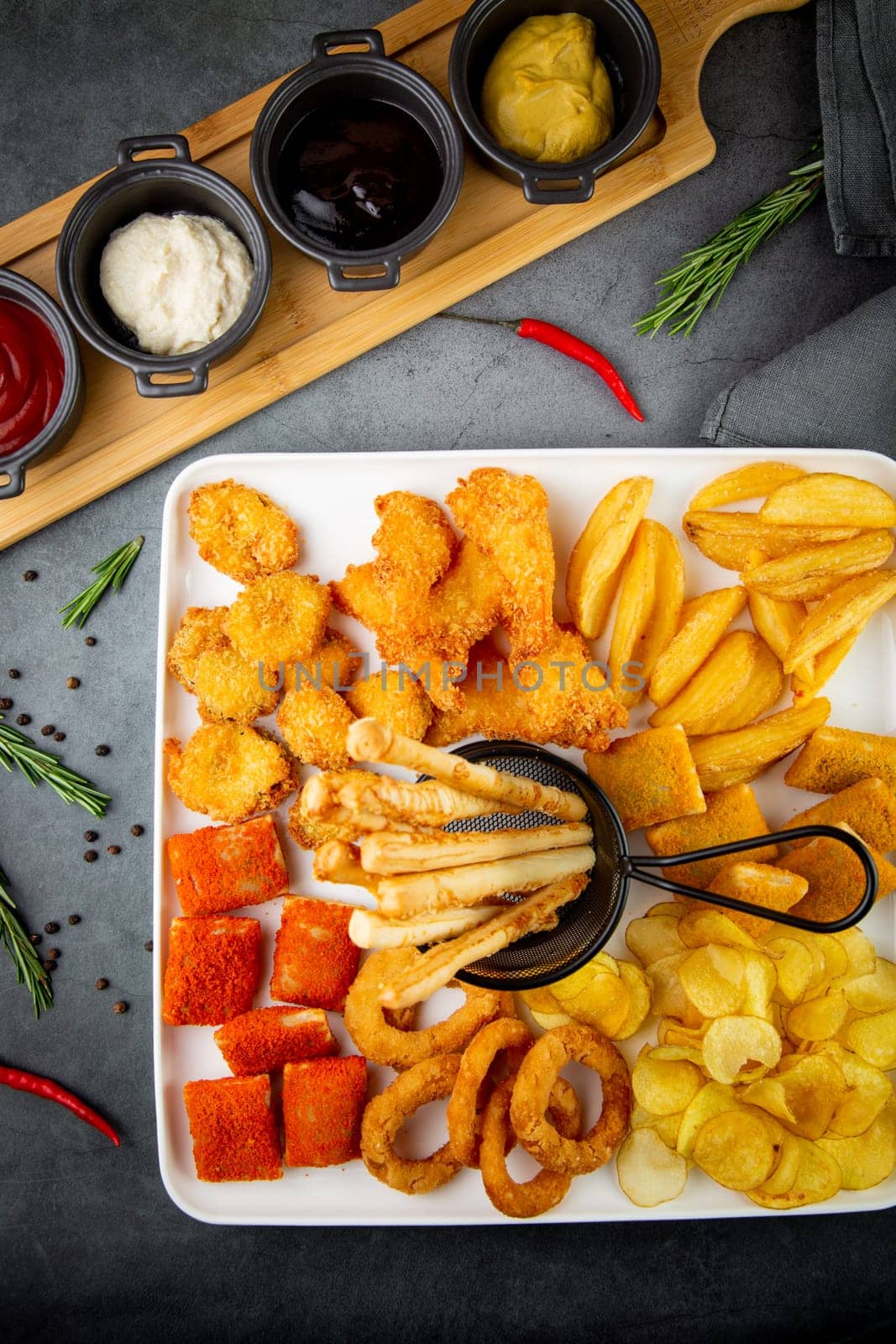 beer set with nuggets, breaded onion rings, fries and sauces top view by tewolf