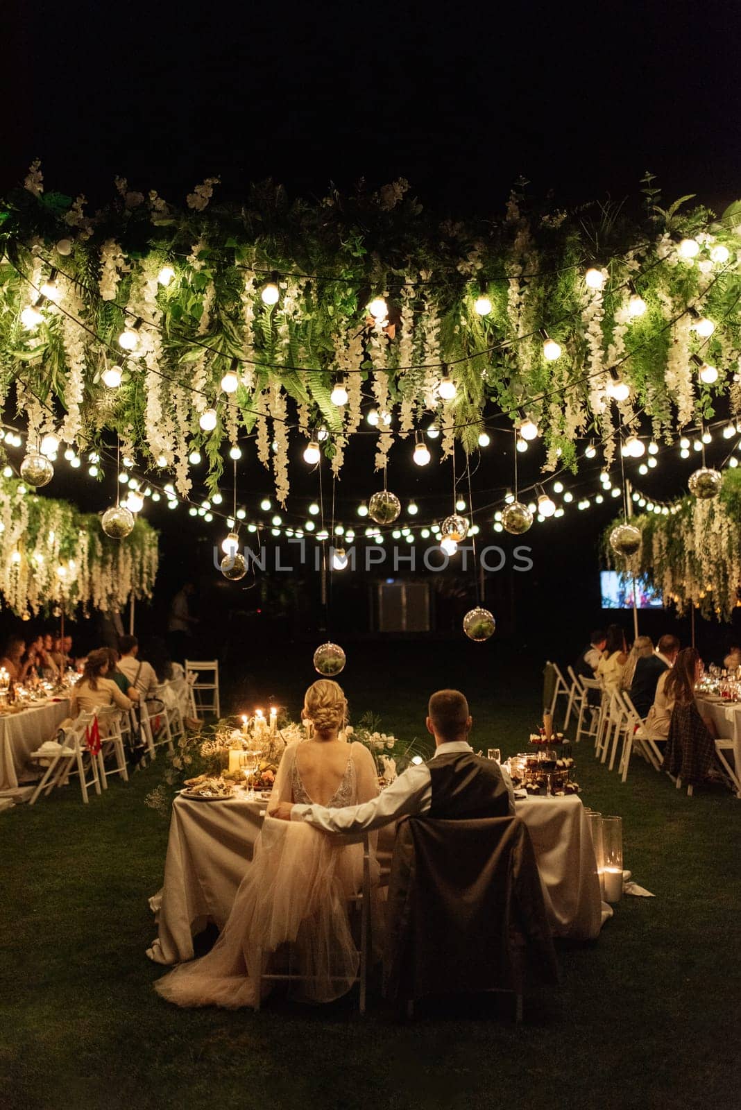 evening wedding family dinner in the forest with light bulbs and candles