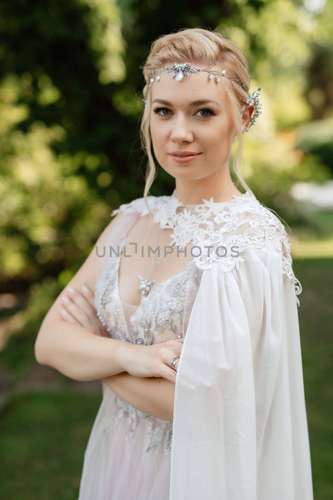 portrait of a happy bride in a light light dress on a green meadow in the park wearing elven accessories