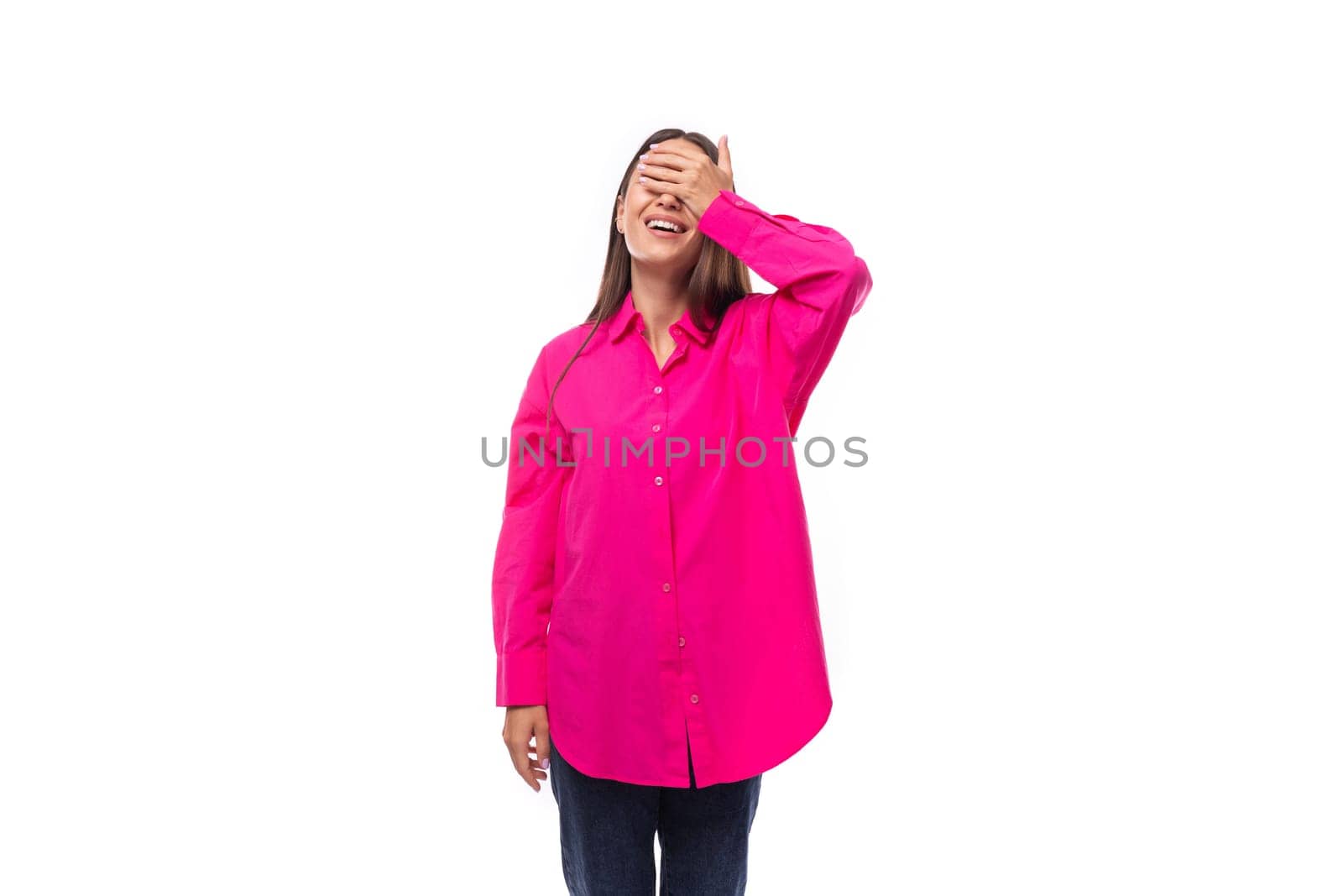 stylish charming young brunette in a bright pink oversized shirt on a white background with copy space.