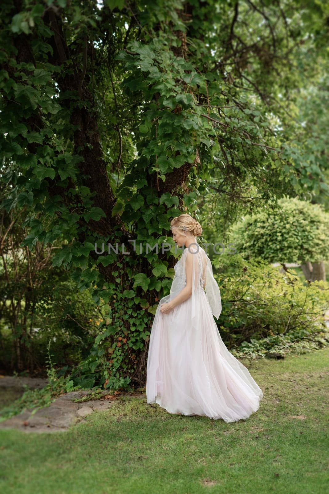 portrait of a happy bride in a light light dress on a green meadow in the park wearing elven accessories