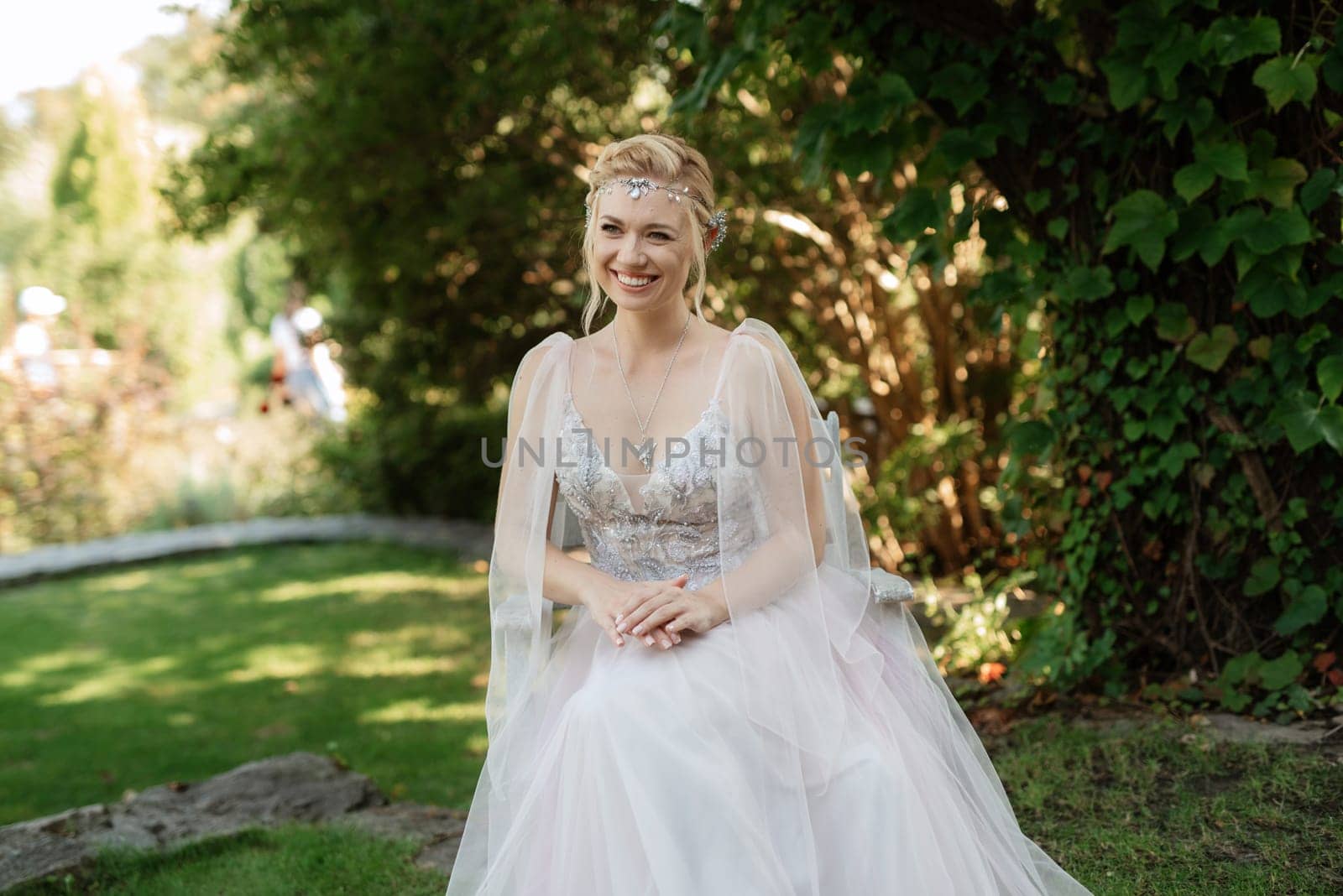 portrait of a happy bride in a light light dress on a green meadow in the park wearing elven accessories