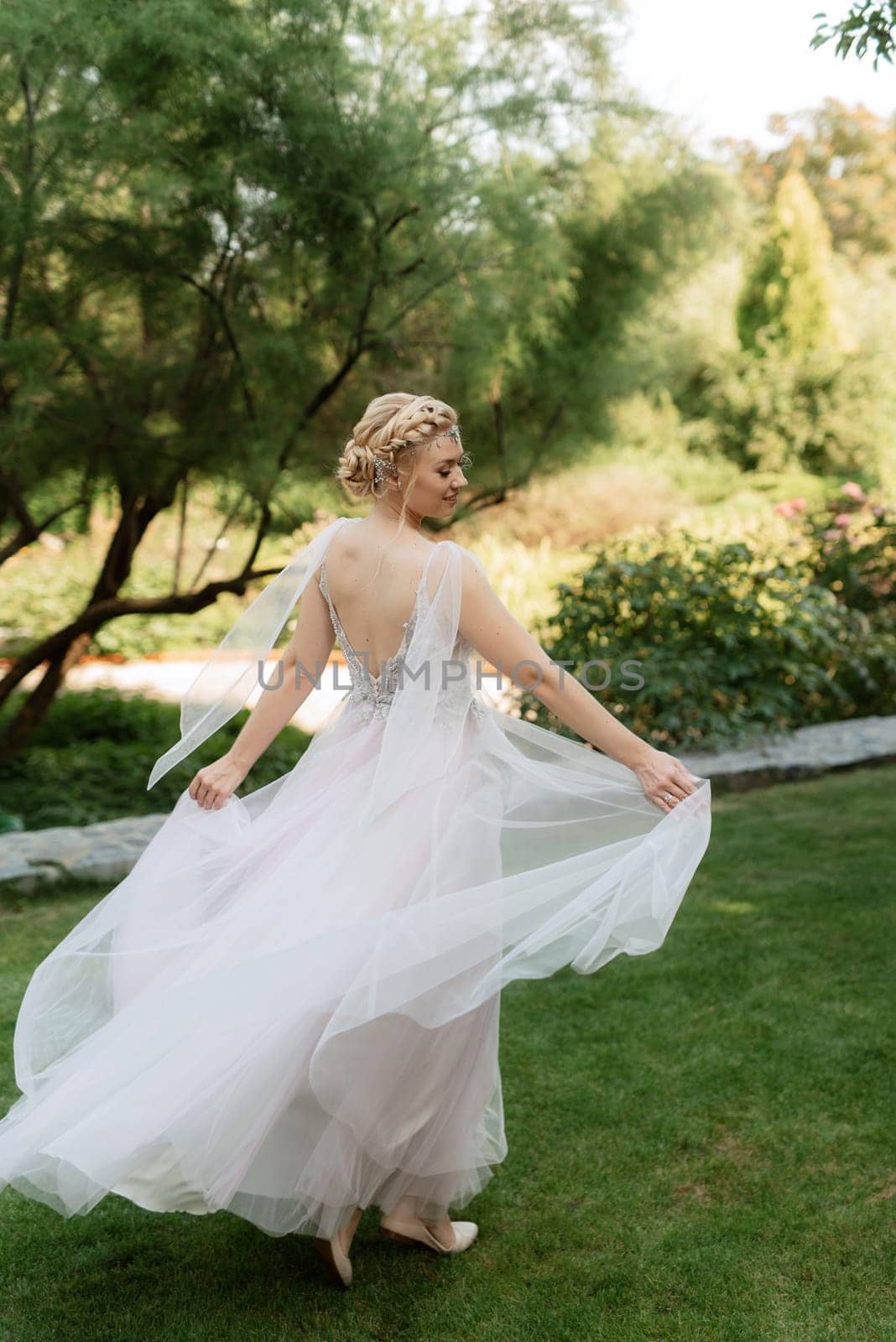 portrait of a happy bride in a light light dress on a green meadow in the park wearing elven accessories