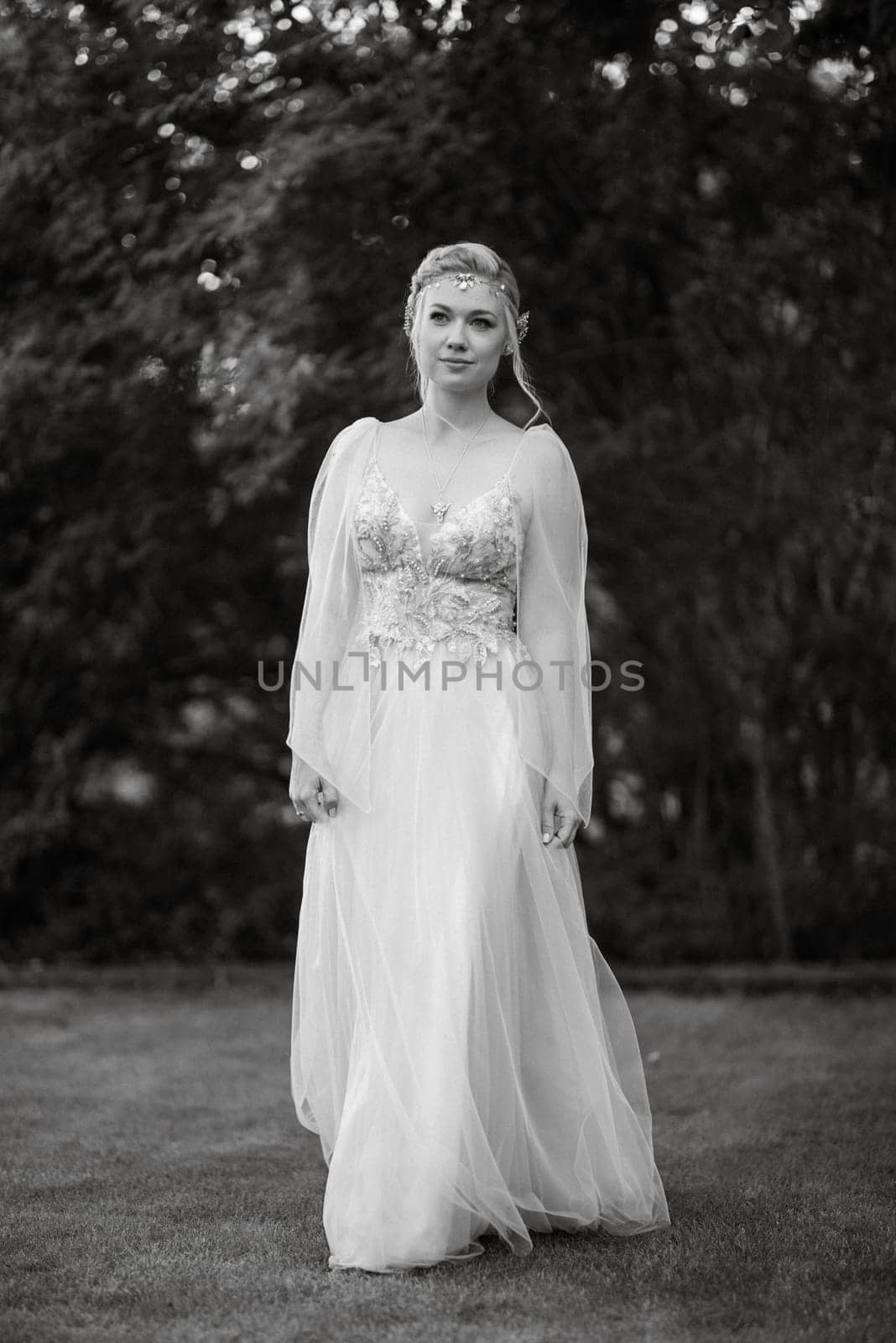 portrait of a happy bride in a light light dress on a green meadow in the park wearing elven accessories