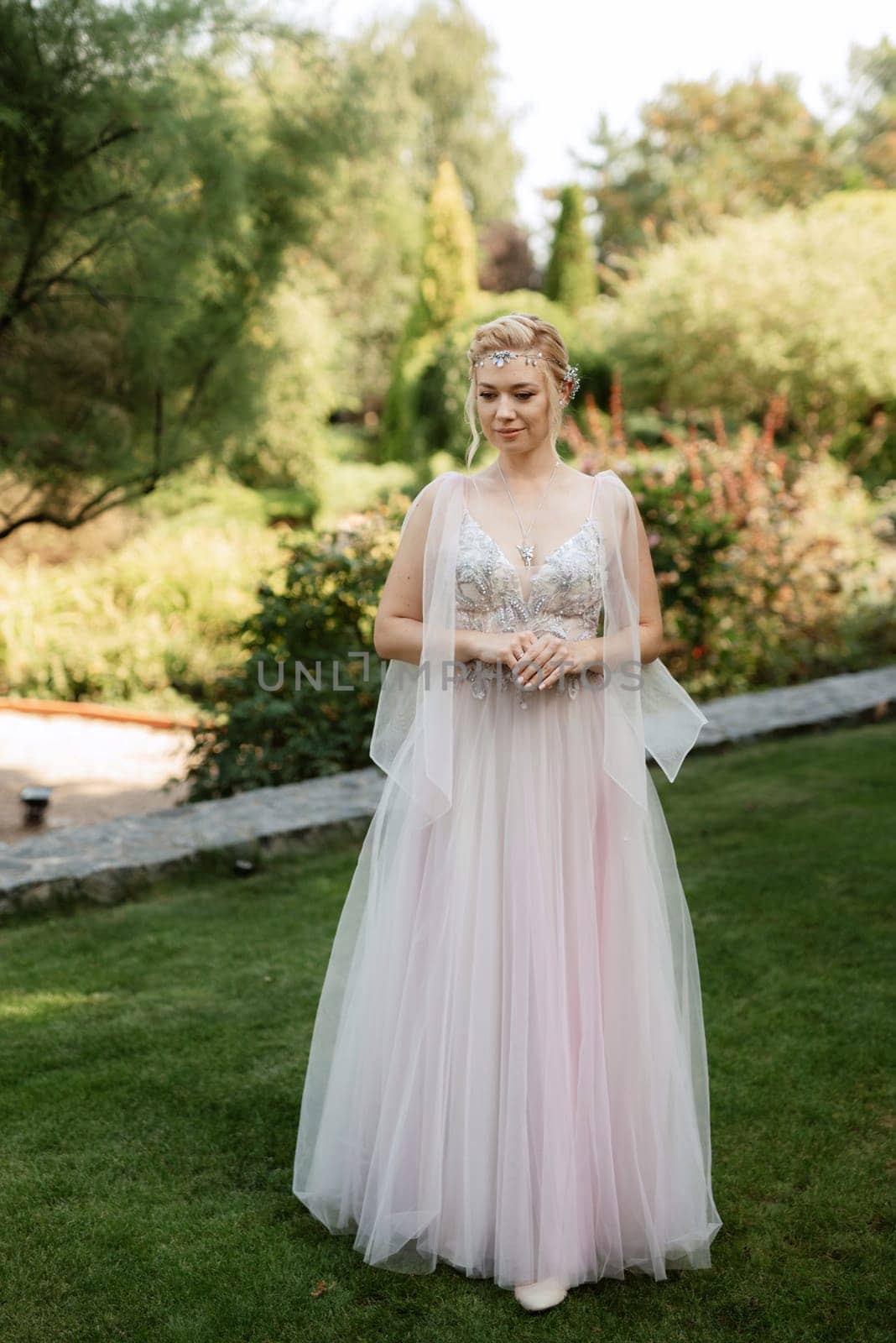 portrait of a happy bride in a light light dress on a green meadow in the park wearing elven accessories