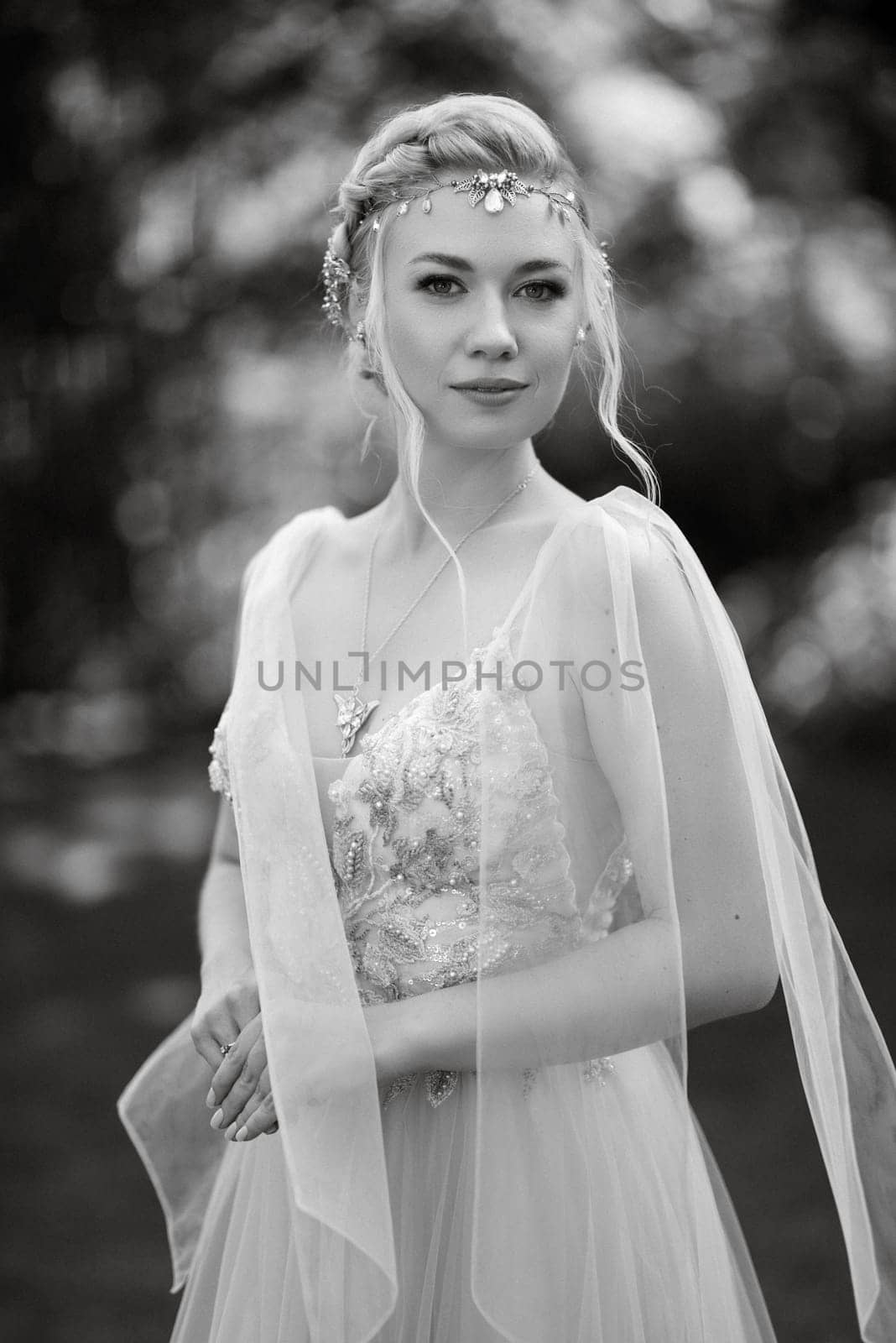 portrait of a happy bride in a light light dress on a green meadow in the park wearing elven accessories