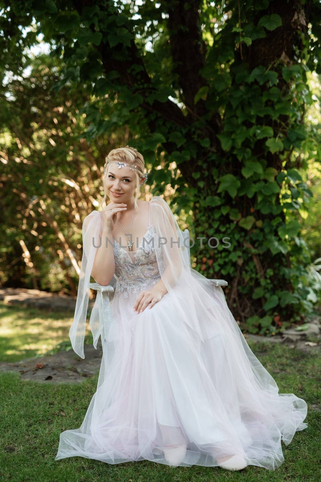 portrait of a happy bride in a light light dress on a green meadow in the park wearing elven accessories