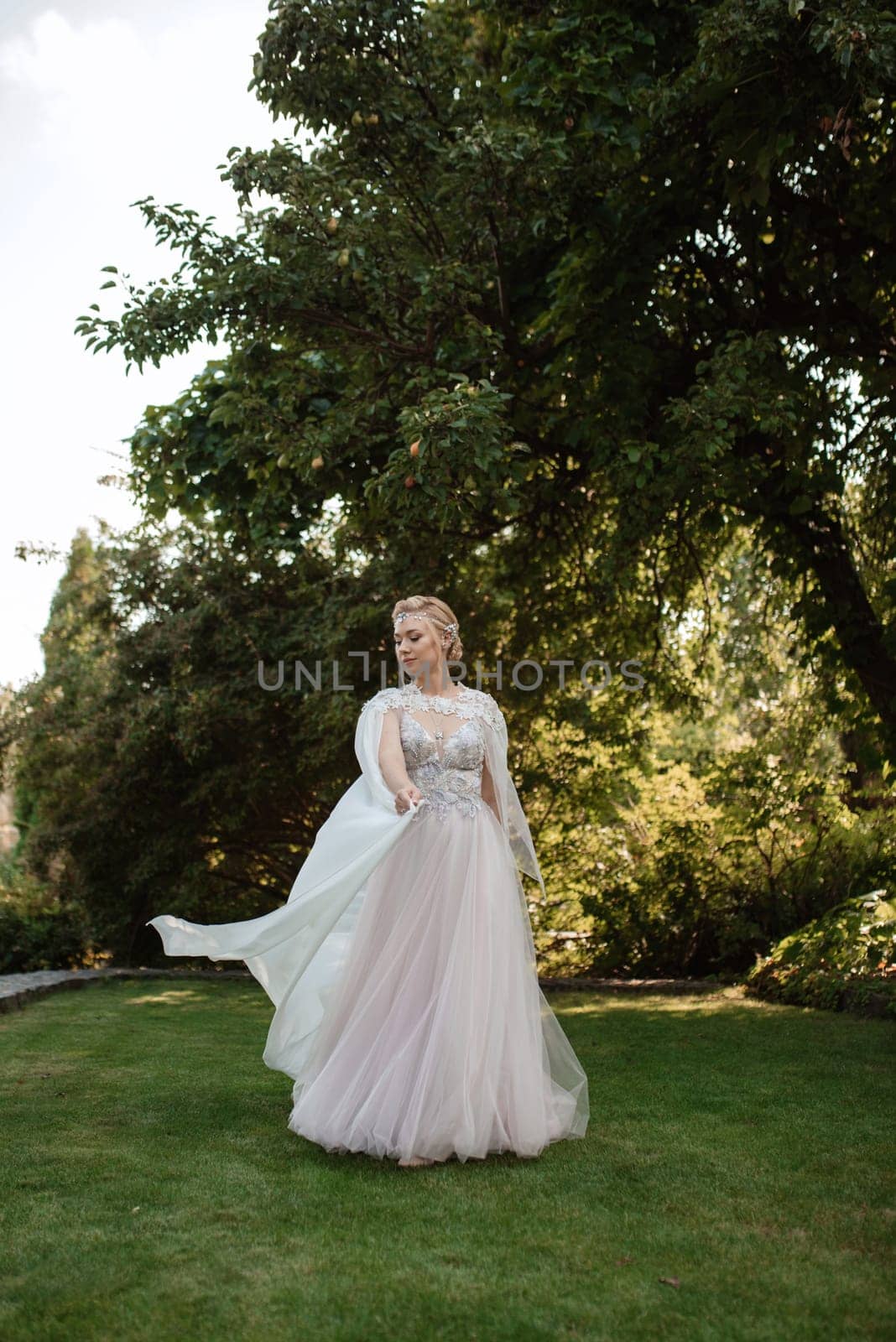 portrait of a happy bride in a light light dress on a green meadow in the park wearing elven accessories