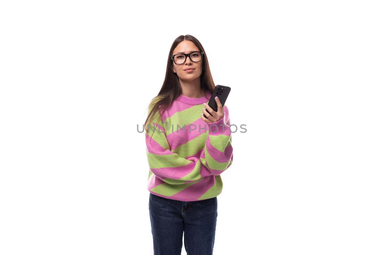 young cheerful charming caucasian woman with straight black hair dressed in a stylish autumn striped sweater holds a smartphone in her hand. mobile phone user concept.