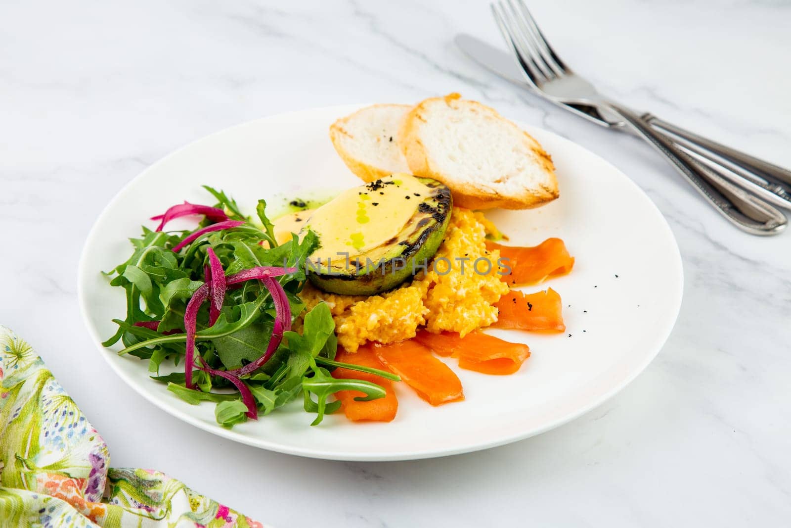 a mix of salmon, arugula salad, white bread and baked avocado with cheese side view by tewolf