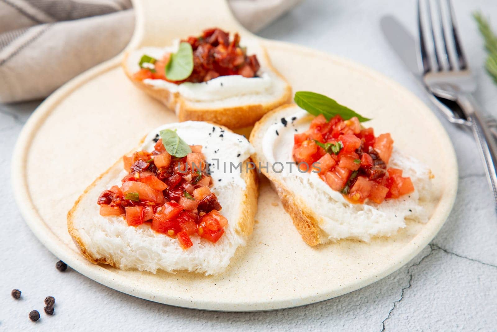 bruschetta with tomatoes and labneh cheese on a light background side view by tewolf