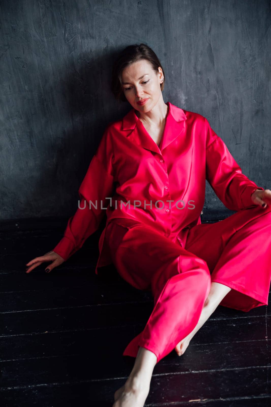 Beautiful slender woman in pink pajamas in dark black room