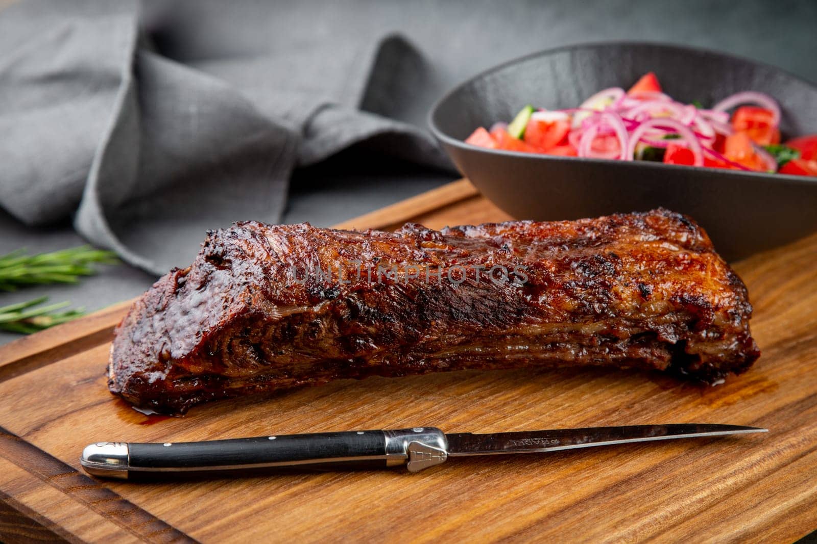 well-done steak with tomato and cucumber salad on a wooden tray