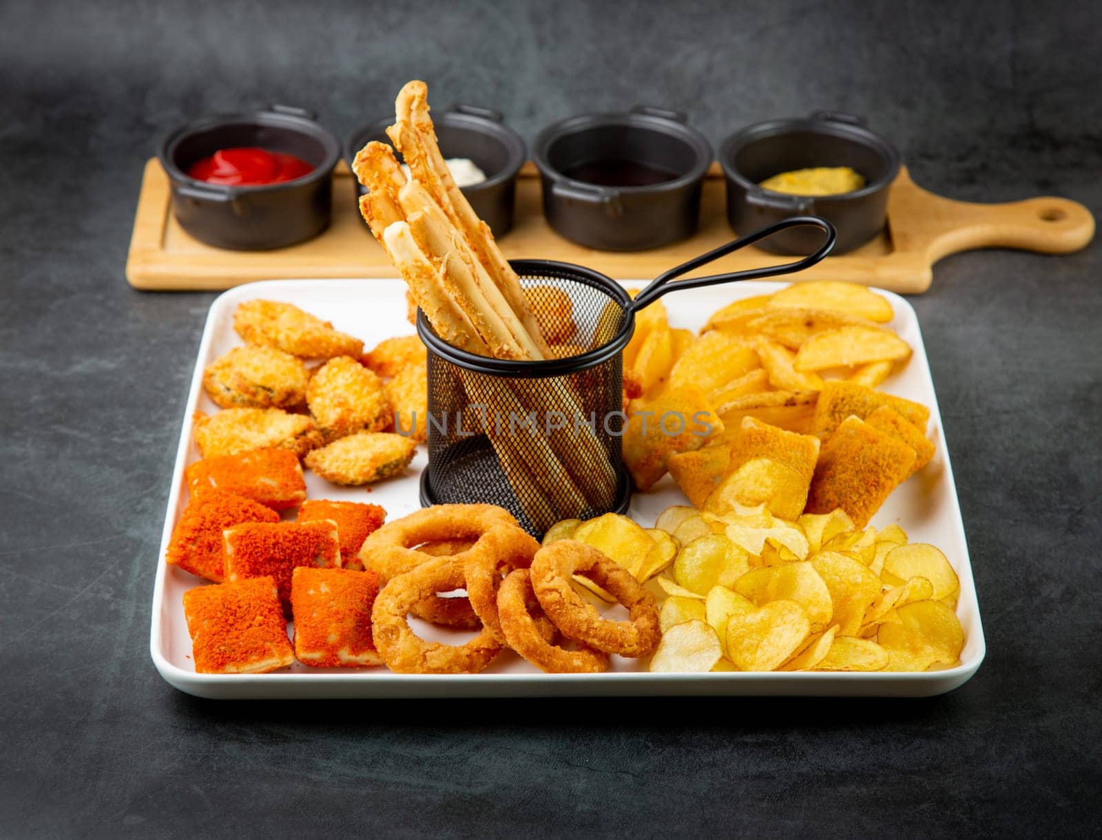 beer set with nuggets, breaded onion rings, fries and sauces side view by tewolf